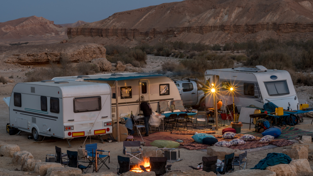 3 campers set up in desert at dusk