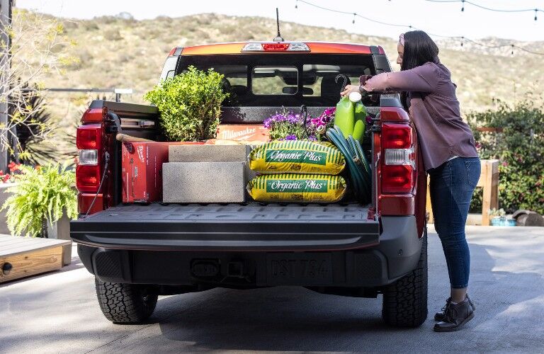 woman loading the cargo bed of her red 2022 Ford Maverick