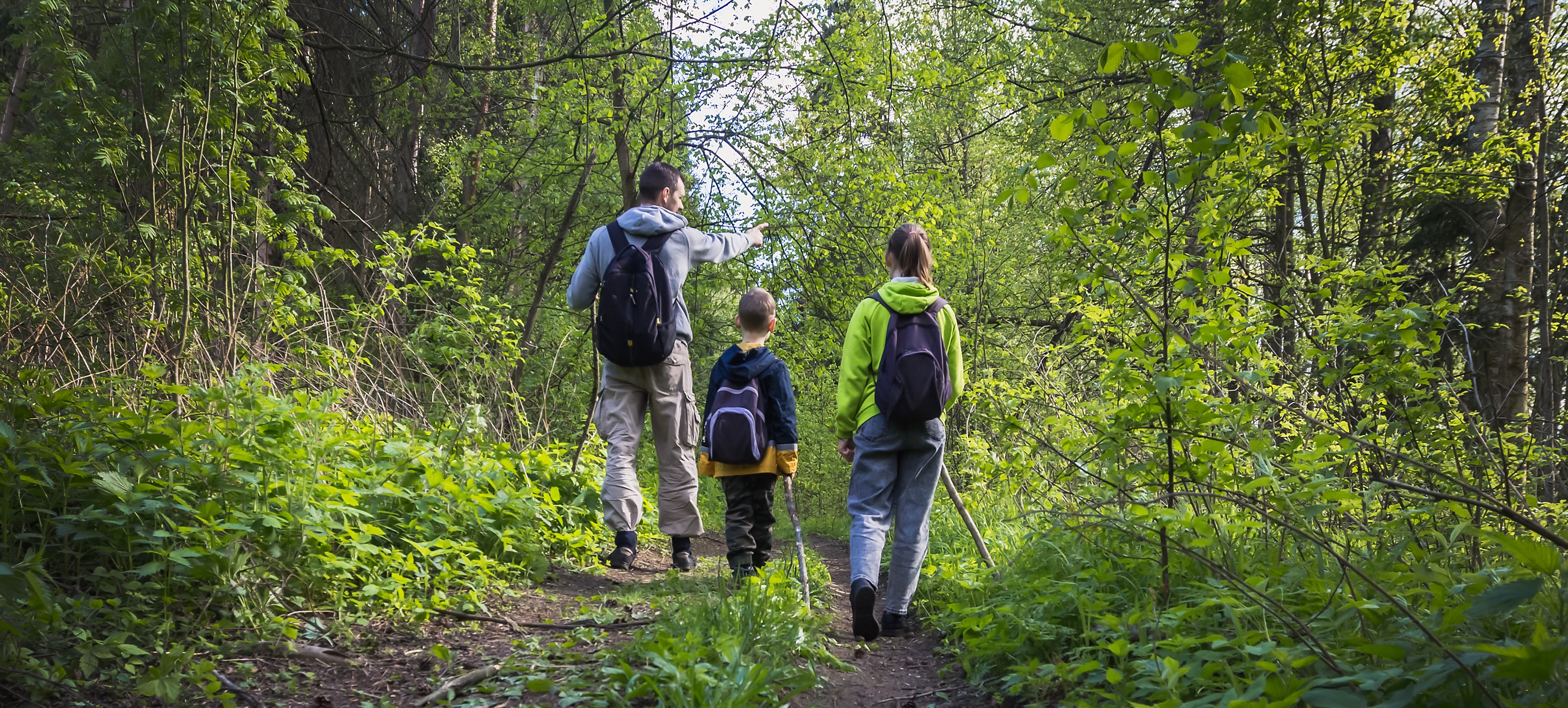 Dad with two kids hiking through the woods