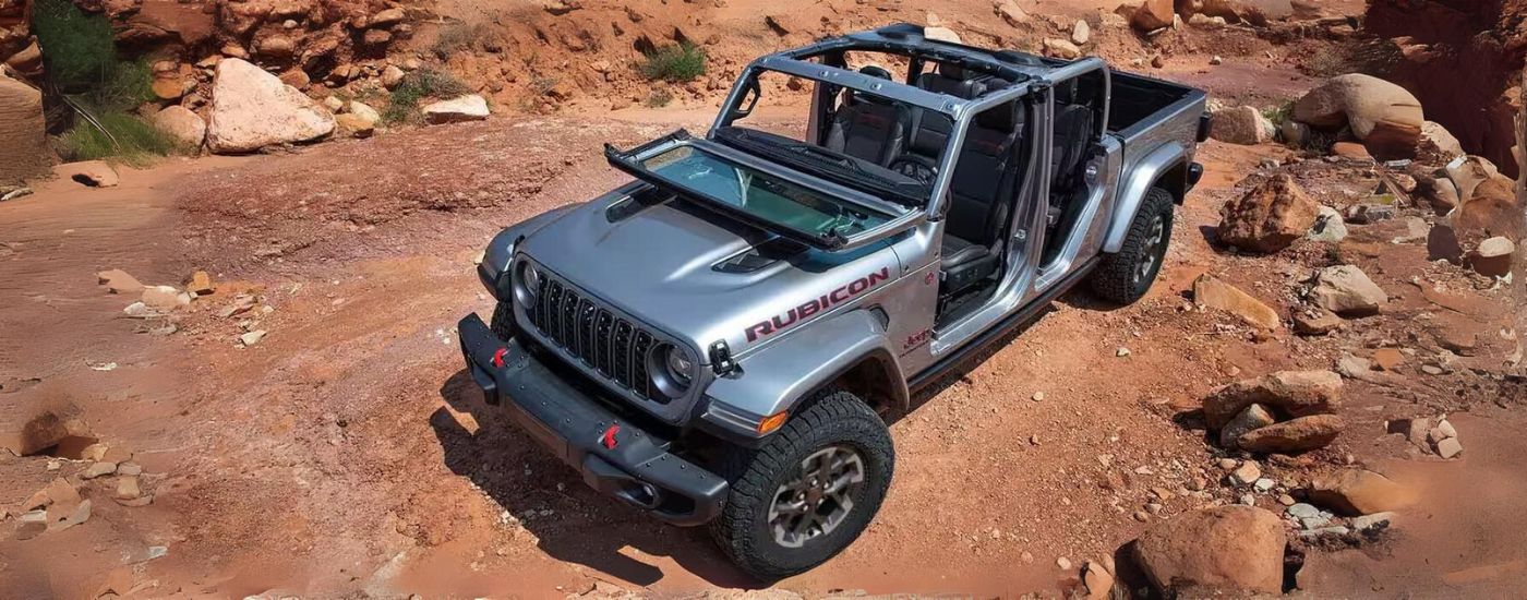 A grey 2024 Jeep Gladiator Rubicon is parked on dirt