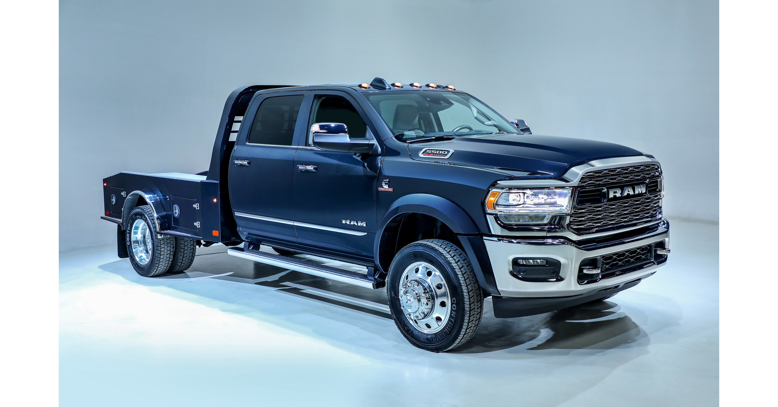 a blue Ram 5500 HS with a flat bed in a front side view with a background that has a blueish hue