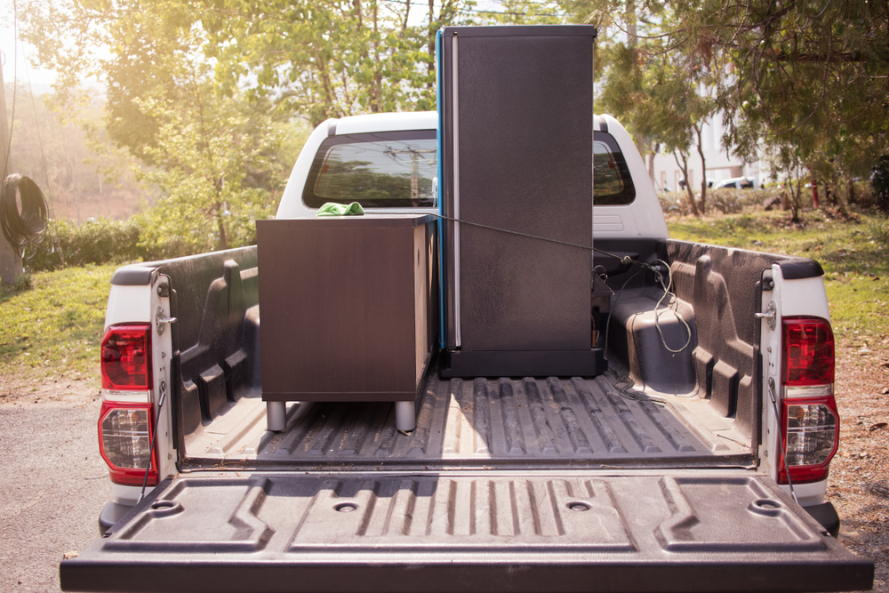 white pickup truck carrying furniture in its bed