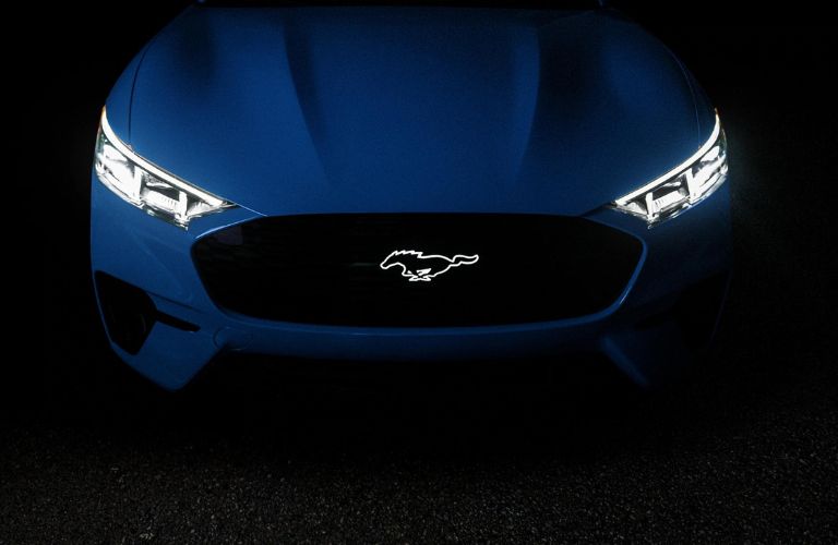 Blue 2024 Ford Mustang Mach-E Front Exterior at Night with Lit Headlights and Grille Badge