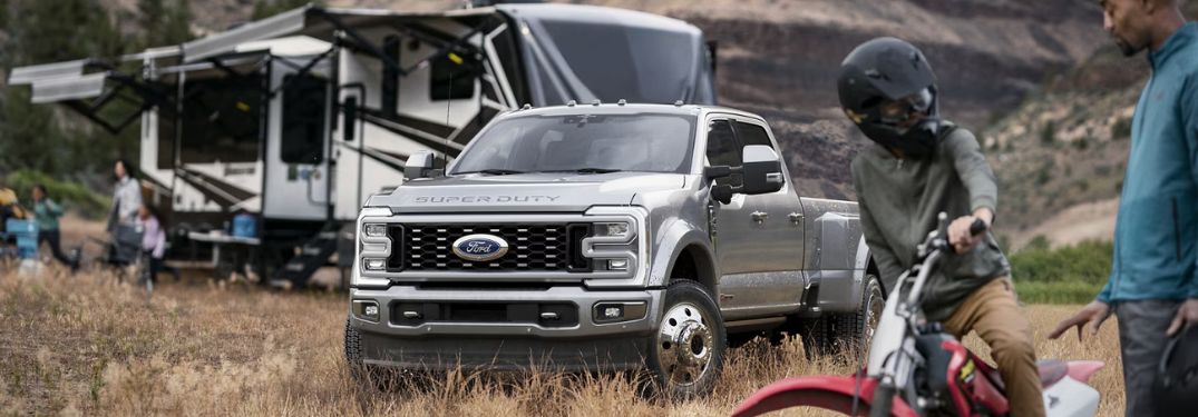 Silver 2024 Ford Super Duty by a Camper and Dirt Bike