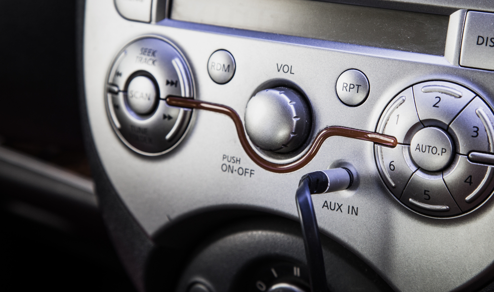 Auxillary cord plugged into an AUX jack inside of a vehicle