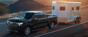 A black chevy silverado 1500 pulling a trailer.