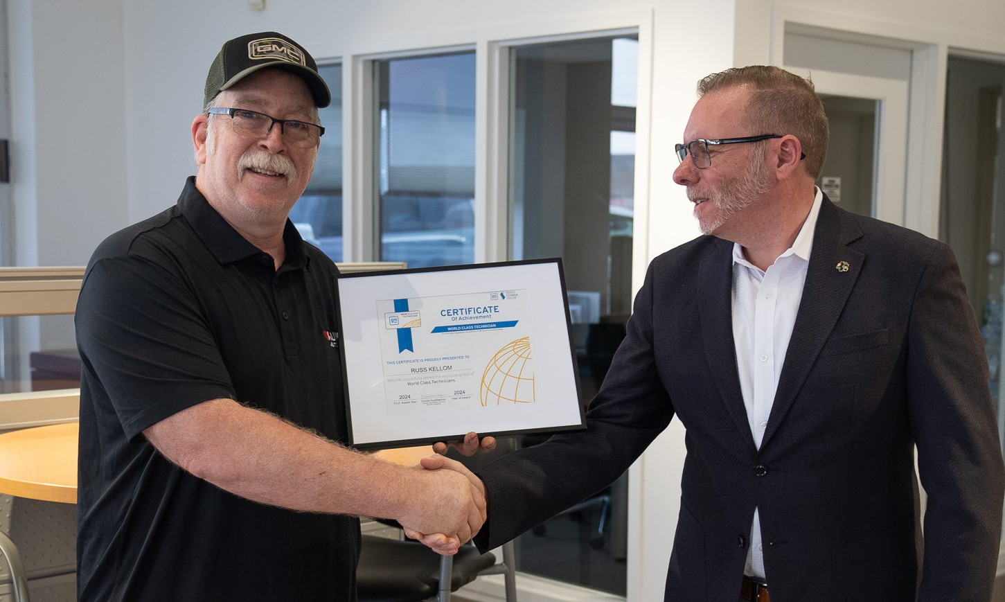 Russ Kellom, technician at Kunes Buick GMC of Stoughton, accepting GM World Class Technician award while shaking hands with Chris Miranda, Kunes Auto Group Regional General Manager and Regional Service Manager of Madison region