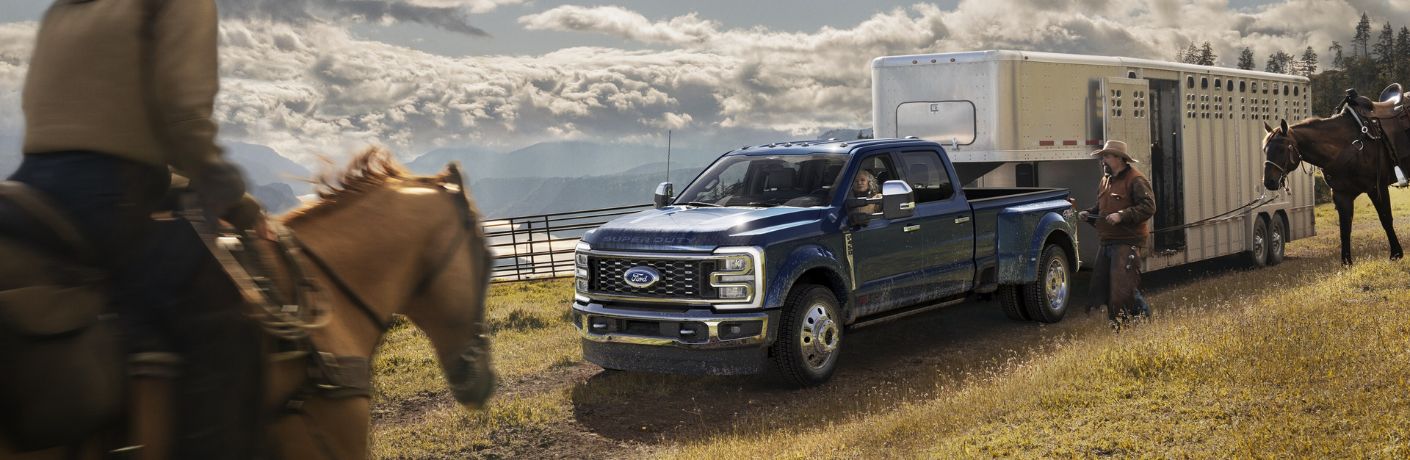 Blue 2024 Ford Super Duty Towing a Horse Trailer on a Ranch