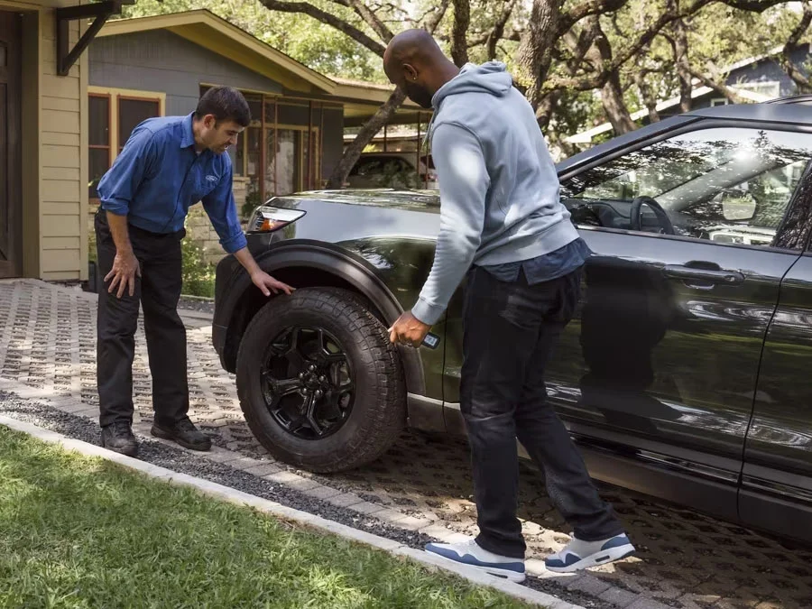 Image of Ford mobile service employee checking client's green ford SUV