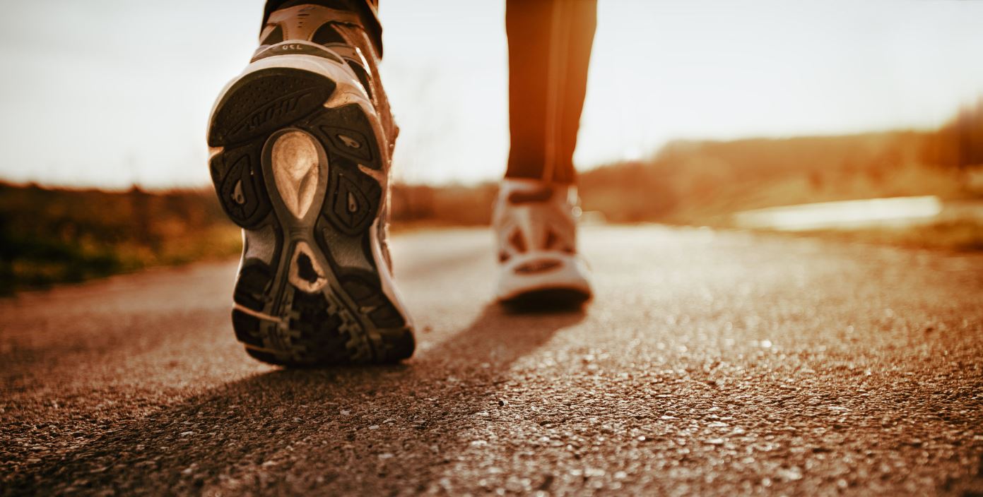 close up of a walker's tennis shoes as they walk on the pavement