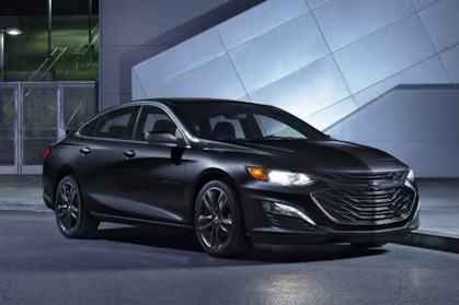 a black metallic car parked beside a building