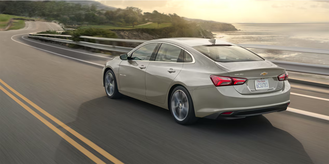 A chevy Malibu drving on a road.