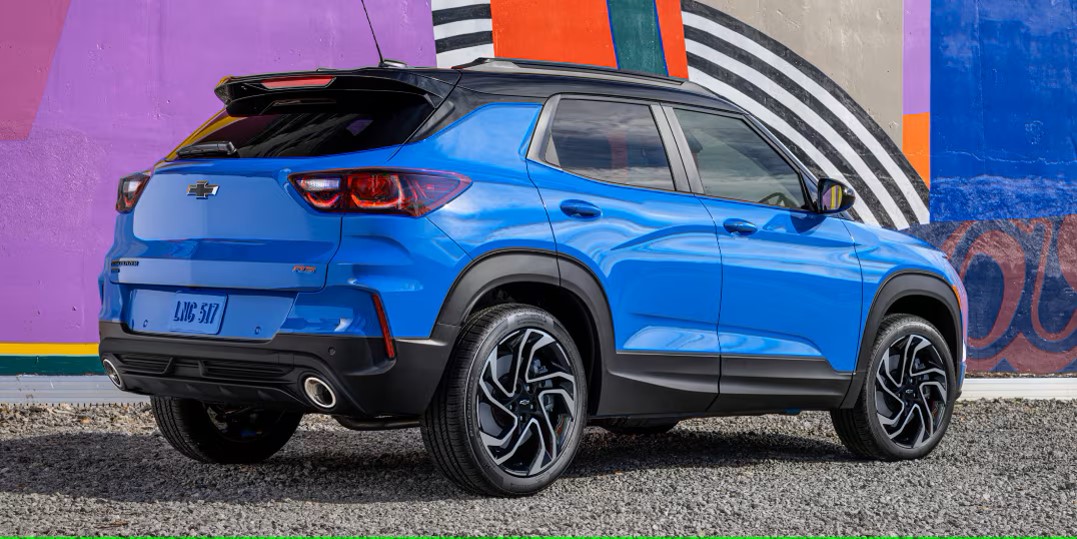 a blue compact suv parked on a gravel road next to a building