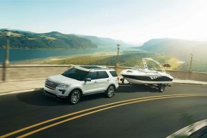 white 2018 Ford Explorer towing a boat along a coastal highway