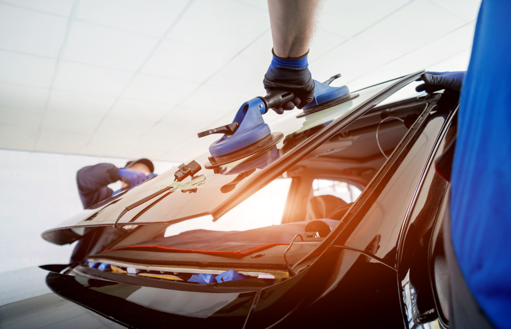 body shop technicians replacing using suction cup tools to replace a vehicle's windshield