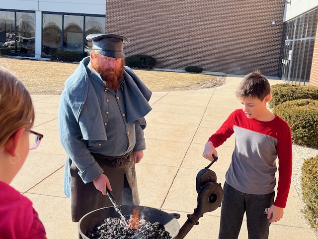 a blacksmith teaching kids how to forge medal