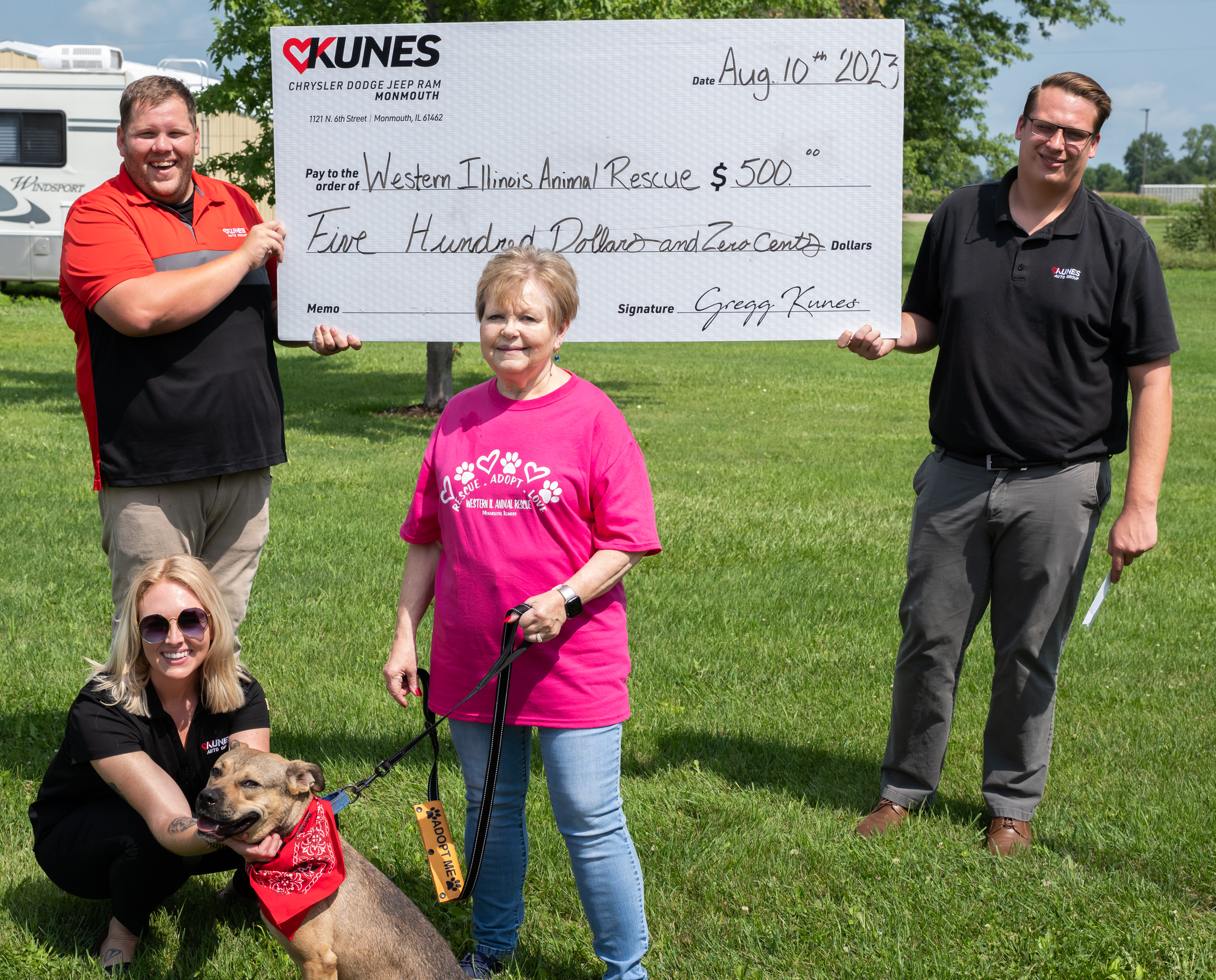 Jan Helms is presented a $500 check for WIAR from two general managers from Kunes Auto Group