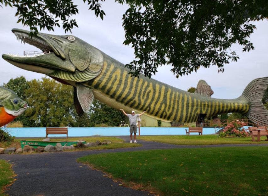 a man standing in front of the enormous musky shaped building in Hayward, WI