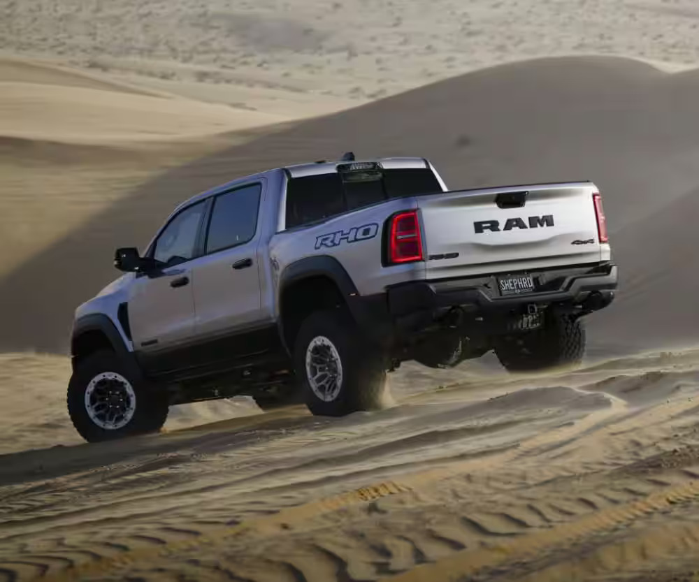 A gray 2025 Ram 1500 driving in sand.