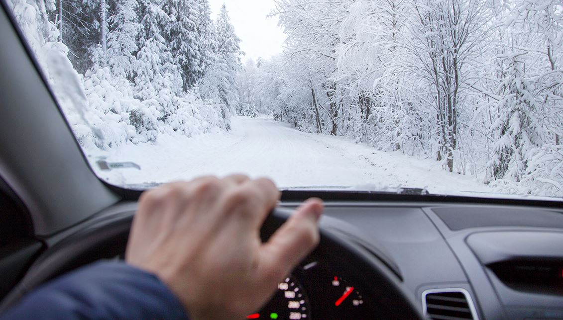 individual drives their car on a snow-covered road during winter