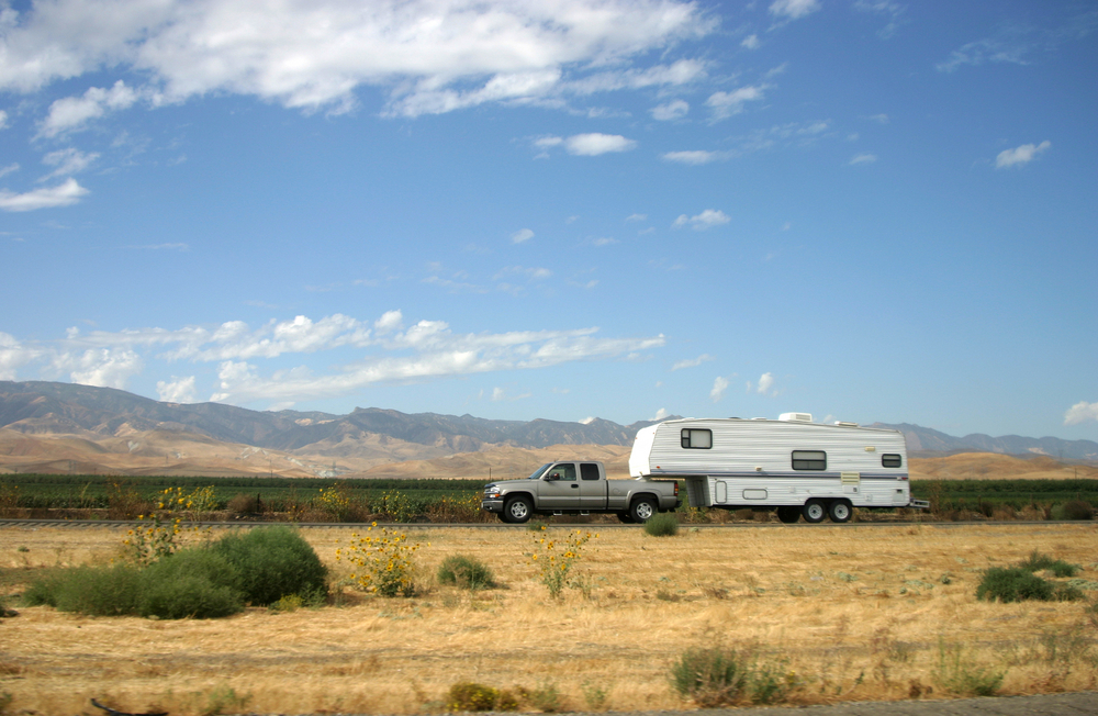 pickup truck towing acmper on a remote desert road