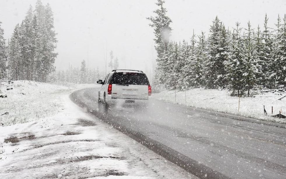 white SUV drives down a snowy road