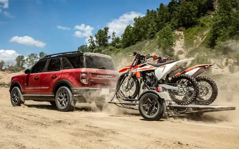 image of red ford bronco towing motorbikes