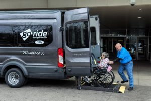 Ford GoRide driver helping an elderly lady in a wheelchair get into a Ford GoRide van