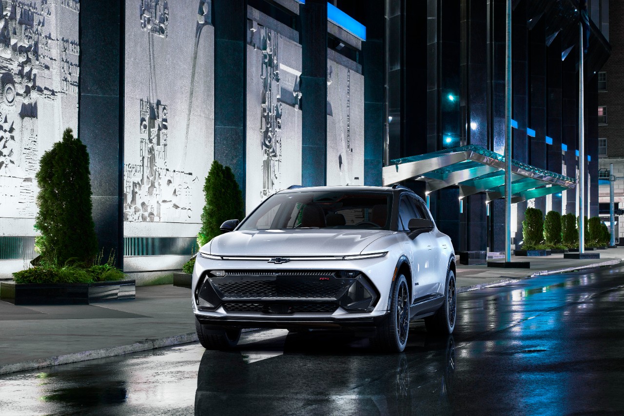 Front view of 2024 Chevrolet Equinox EV 3RS in Iridescent Pearl parked on a city street at night.