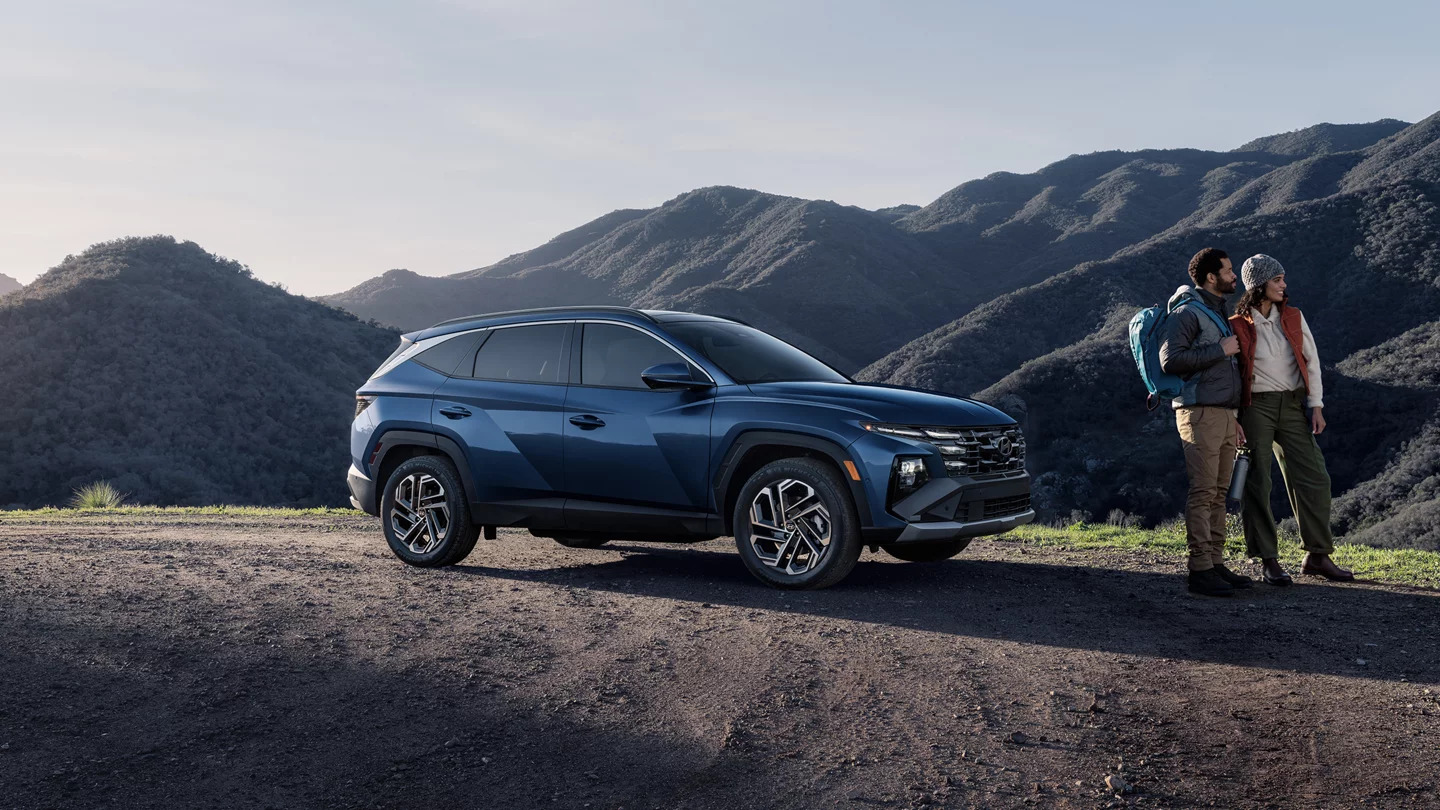 A man and woman standing near a Hyundai Tucson.