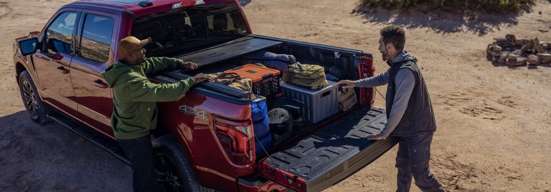 Two Men Loading Cargo in Bed of Red 2024 Ford F-150