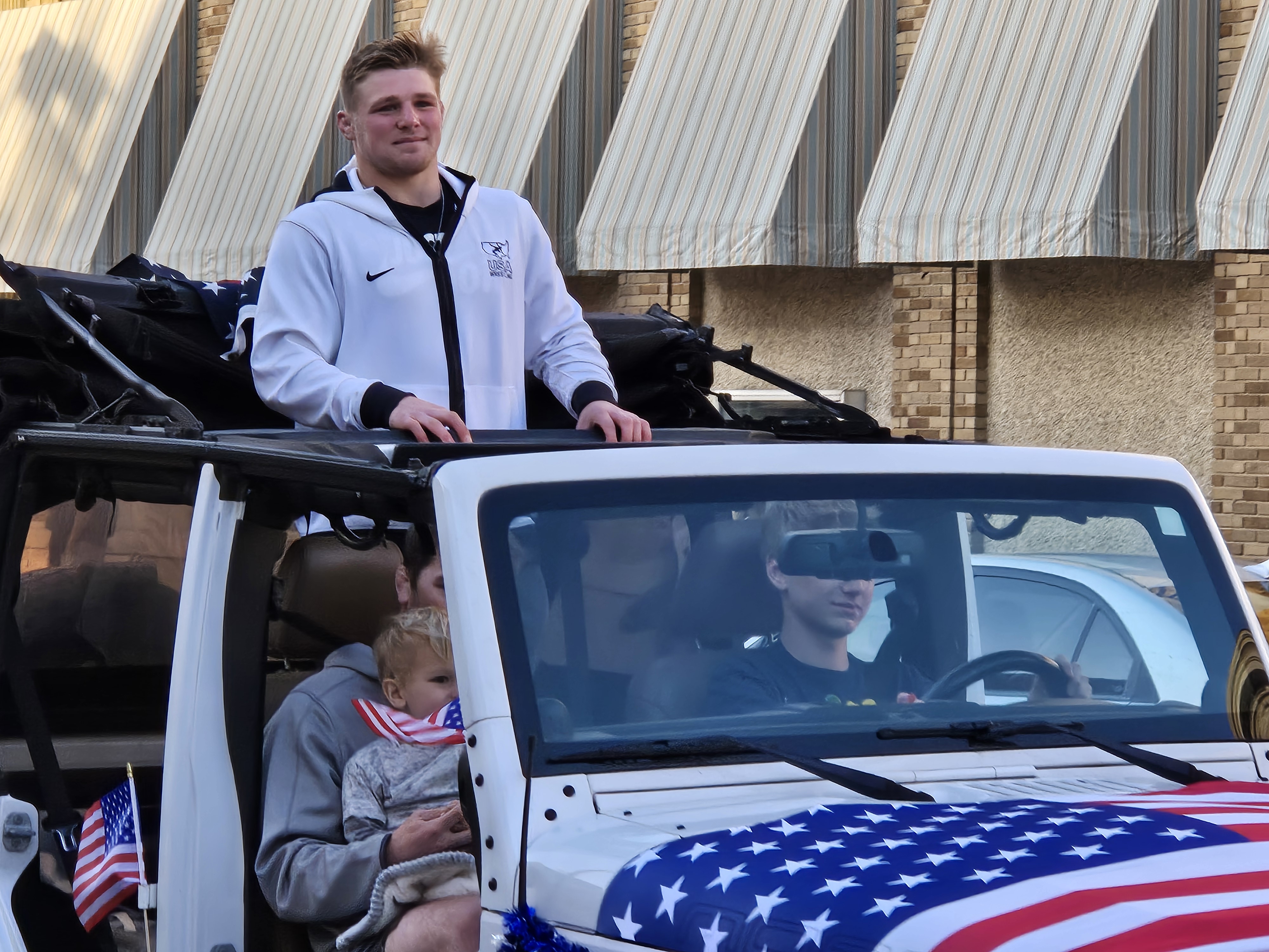 Payton Jacobson and his family in a white Jeep Wrangler decorated in USA flags