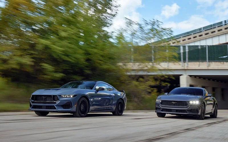 Image of two mustangs driving down highway