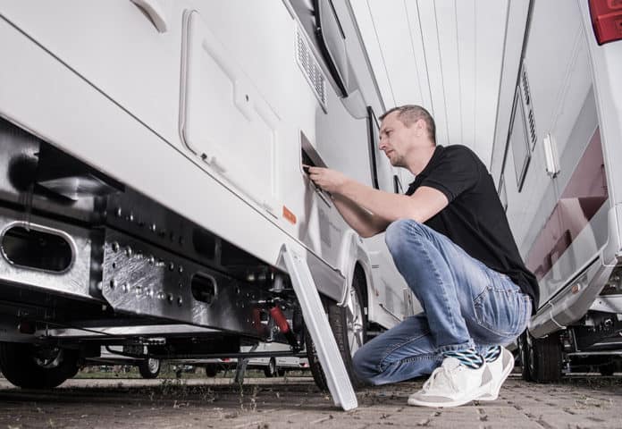 man inspects the exterior of his RV