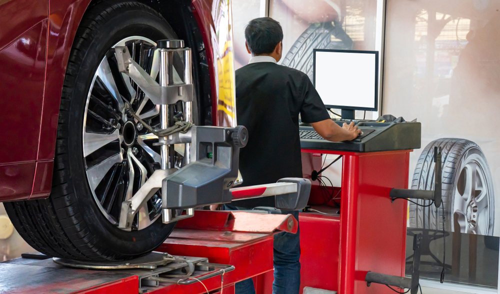 Kunes Service Center expert technician checks a vehicle's wheel alignment on the computer screen while the vehicle is hooked up to the machine