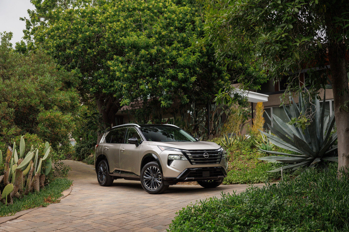 2024 Nissan Rogue in Baja Storm in front of green scenery