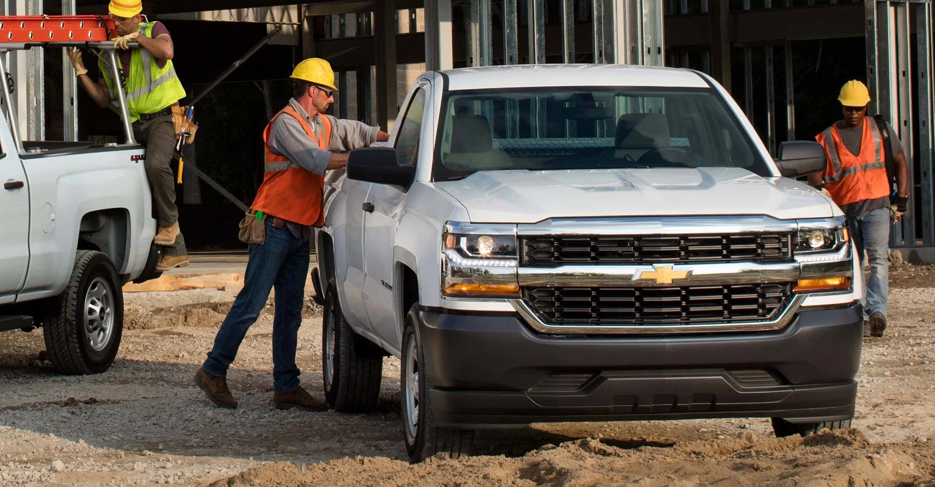 A construction crew of three providing their services while using 2 Chevrolet commercial trucks.