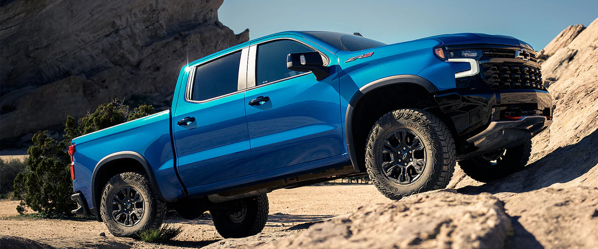 a blue truck driving up a rocky desert background