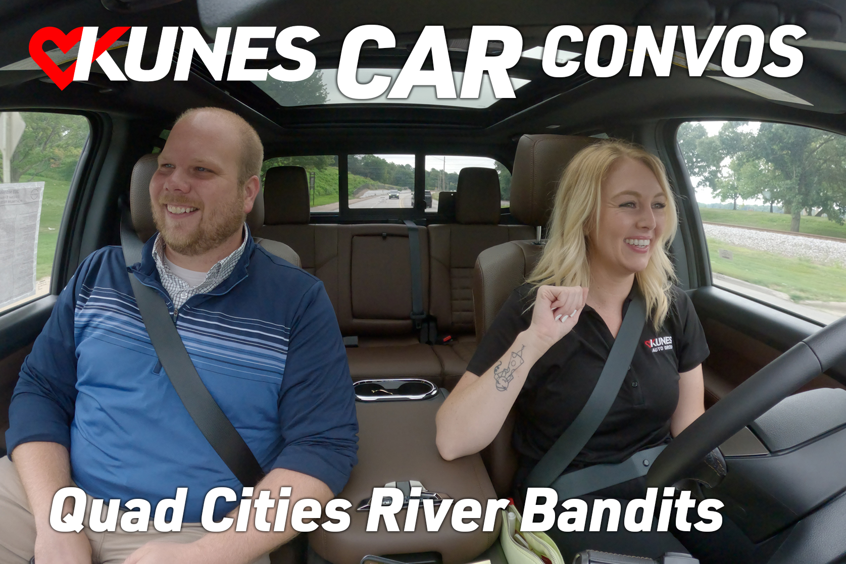 Text: Kunes Car Convos; Quad Cities River Bandits; Pictured: Paul Kleinhans-Schulz, General Manager of the Quad Cities River Bandits and Lauren Johnson, Kunes Auto Group Marketing Manager, driving in a 2023 Nissan Titan Platinum Reserve