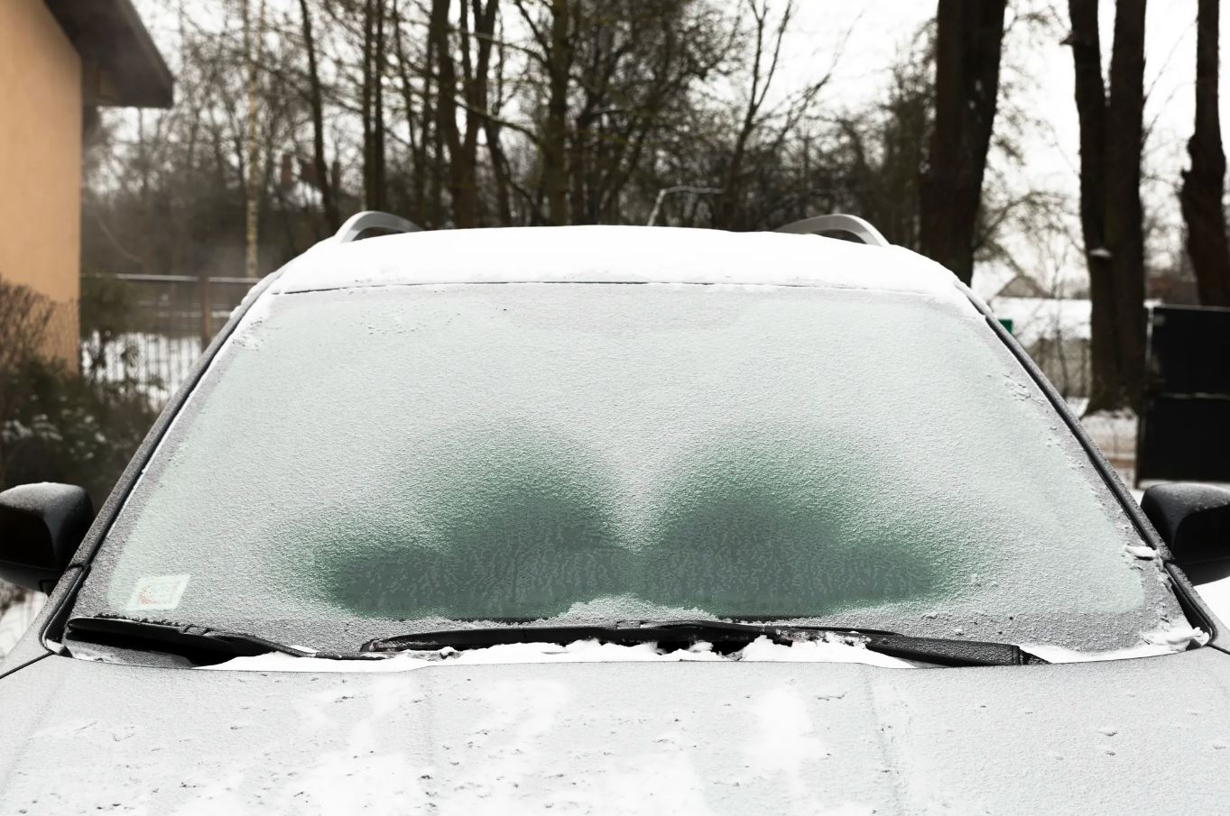 vehicle sits idle while the windshield defrosts on a winter day