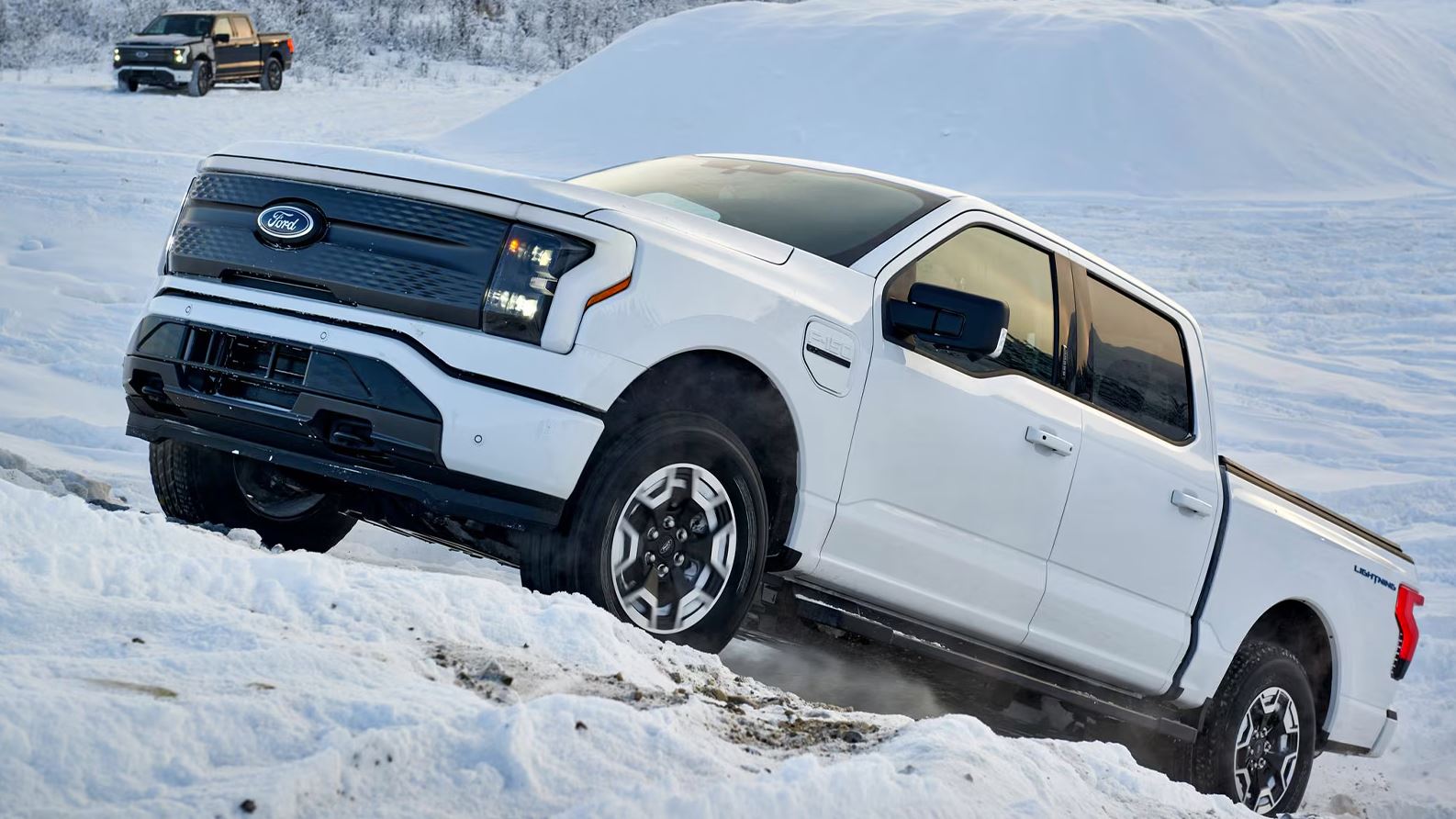 white 2025 Ford Electric Truck driving up a snowy hill