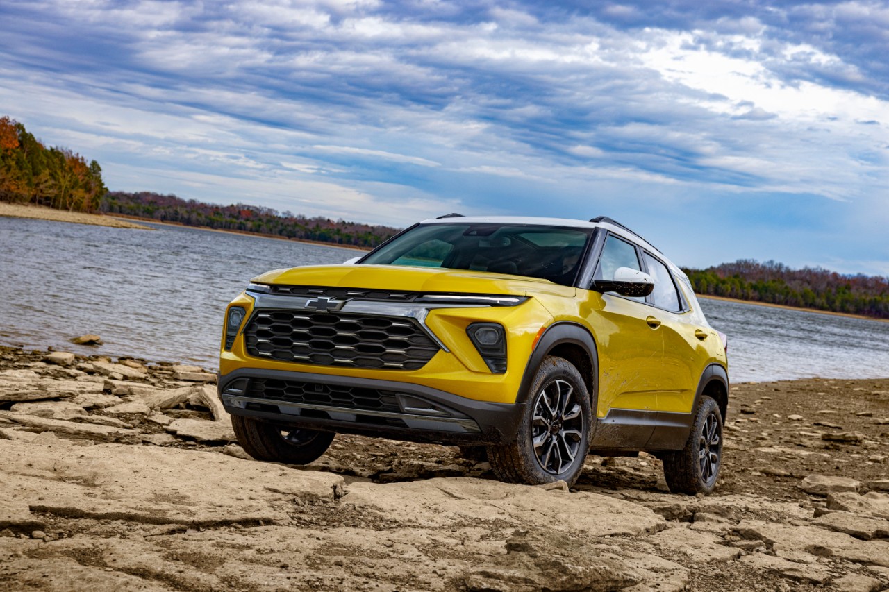 Front 3/4 view of 2024 Chevrolet Trailblazer ACTIV in Nitro Yellow Metallic parked on a rock bank in front of a lake.