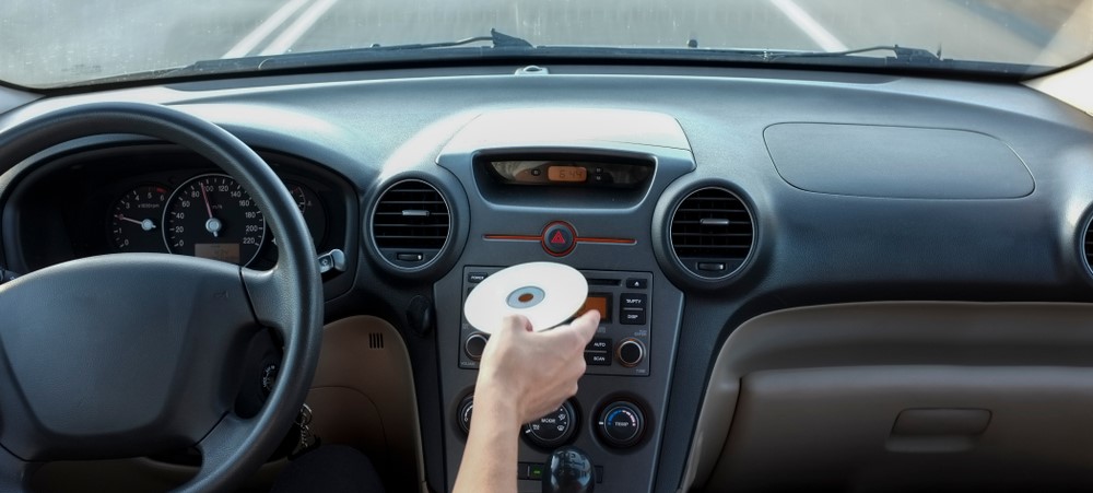 driver inserting a CD into their car's CD player