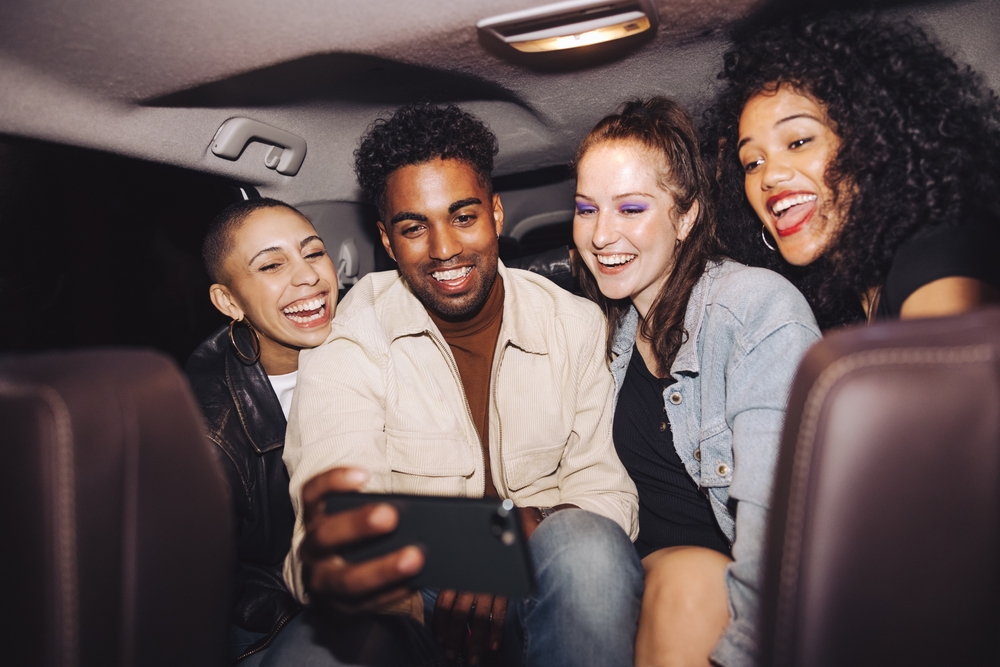 young people take a selfie together in the back of a car