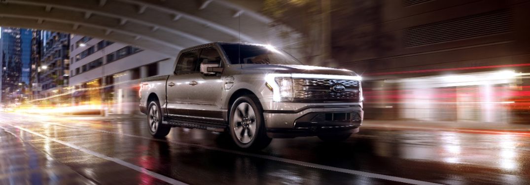 Gray 2023 Ford F-150 Lightning Driving on a City Street at Night