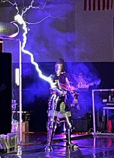 man dressed as a knight drawing his sword as an electric bolt comes out of a tesla coil