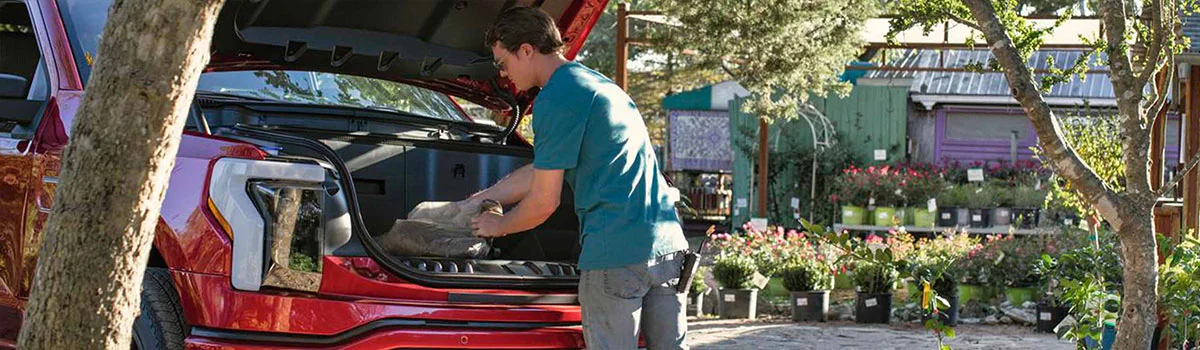 image of man removing luggage from for truck front storage compartment