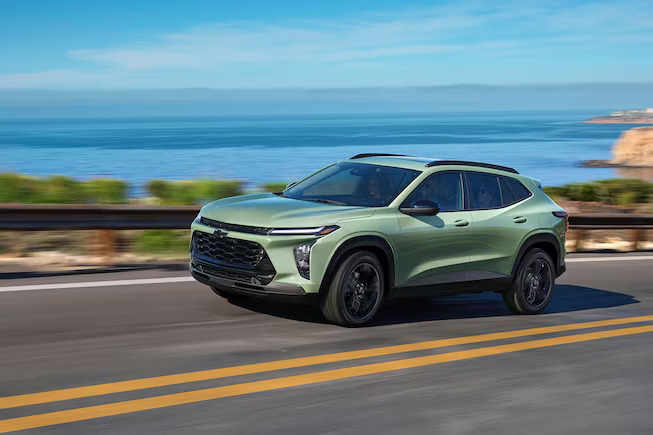 A green Chevrolet Trax driving on a raod.