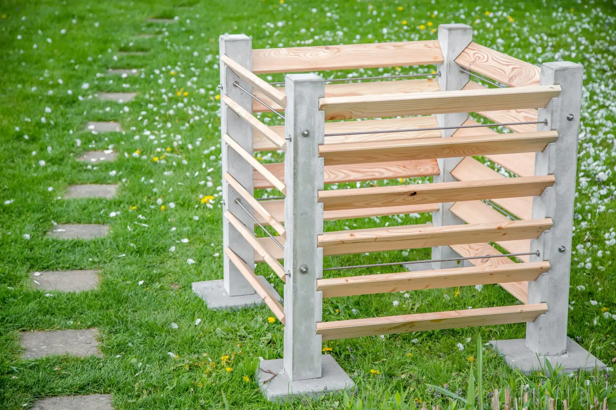 Komposter aus Beton und Lärchenholz steht auf einer grünen Wiese