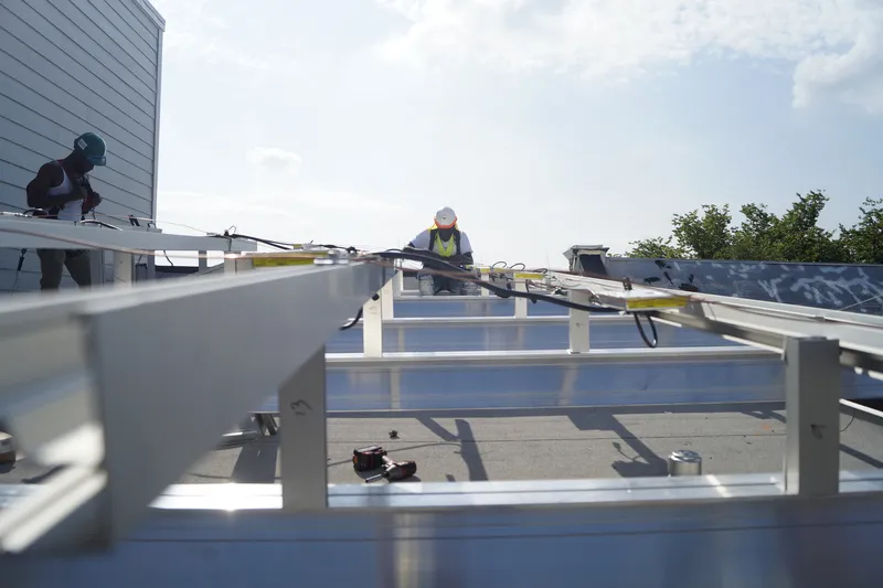 Workers installing solar panel mounting rails and racking on a residential rooftop.